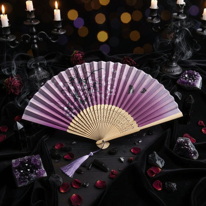 Pink folding fan with floral designs on a light gray background with pink flowers.