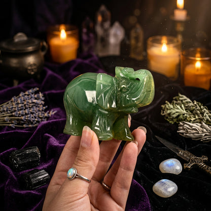 Green jade elephant figurine held in a hand against a beige background