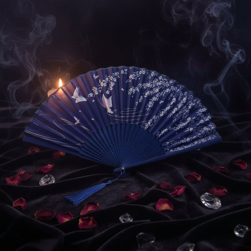 Blue folding fan with floral design on a white background with pink flowers