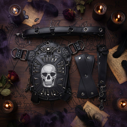 Black faux-leather gothic harness bag with a large silver skull design, studded details, and multiple attached straps and metal rings, shown on a plain white background.