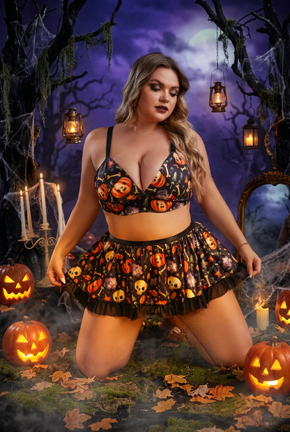 A woman kneels on a black backdrop wearing a Halloween-themed two-piece set with a bralette top and ruffled mini skirt, both printed with pumpkins, skulls, and spiders. The scene includes spooky props like cobwebs, candles, and a mirror.