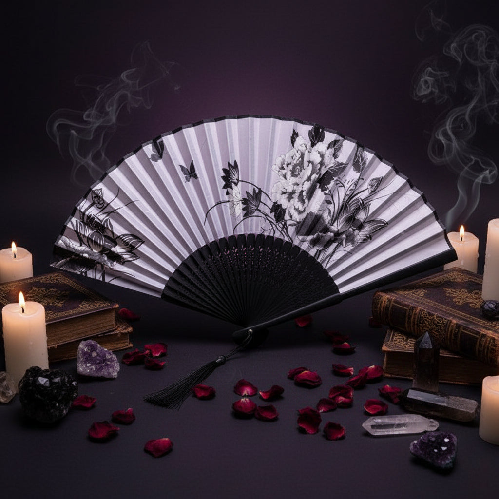 Black and white floral design folding fan with pink flowers on a light background