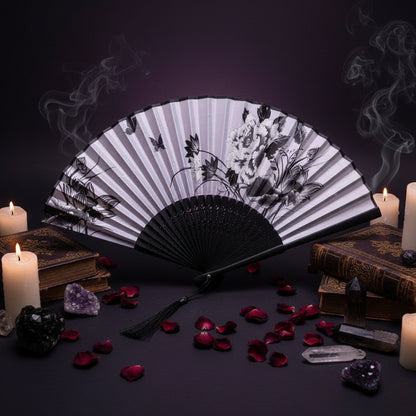 Black and white floral design folding fan with pink flowers on a light background