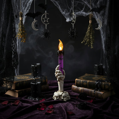 Decorative candle with a skull base on a table with Halloween decorations in the background.