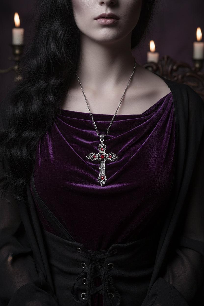 Silver cross pendant with red stones held in a hand against a white background