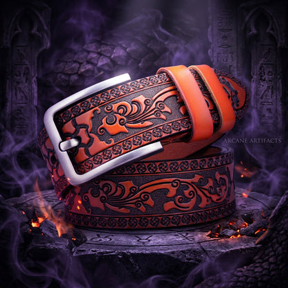 A coiled brown leather belt with a silver buckle, featuring detailed floral tooling and a textured dark inlay.