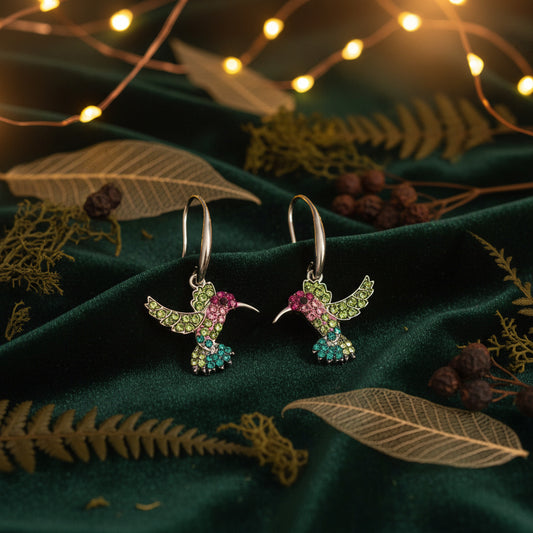 Colorful hummingbird-shaped earrings on a beige background