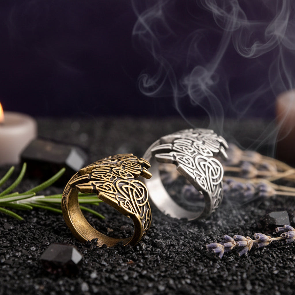 Two bear claw rings, one gold and one silver, on a dark textured surface.