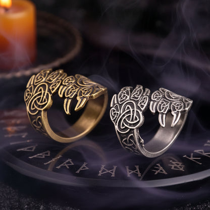 Two ornate rings, one gold and one silver, on a dark textured surface.