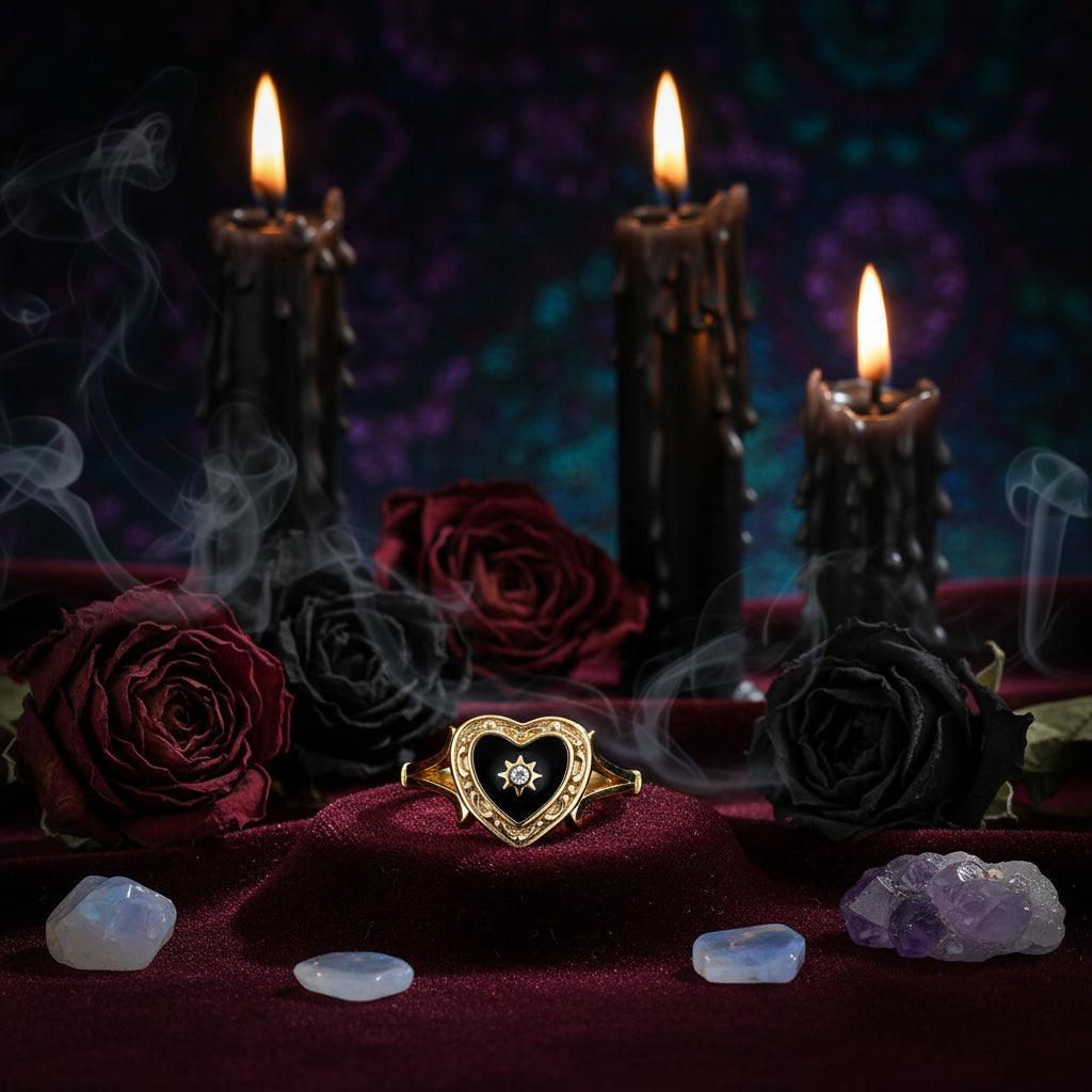 Gold ring with black heart-shaped stone and star detail on a white background