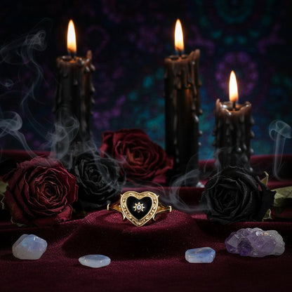Gold ring with black heart-shaped stone and star detail on a white background
