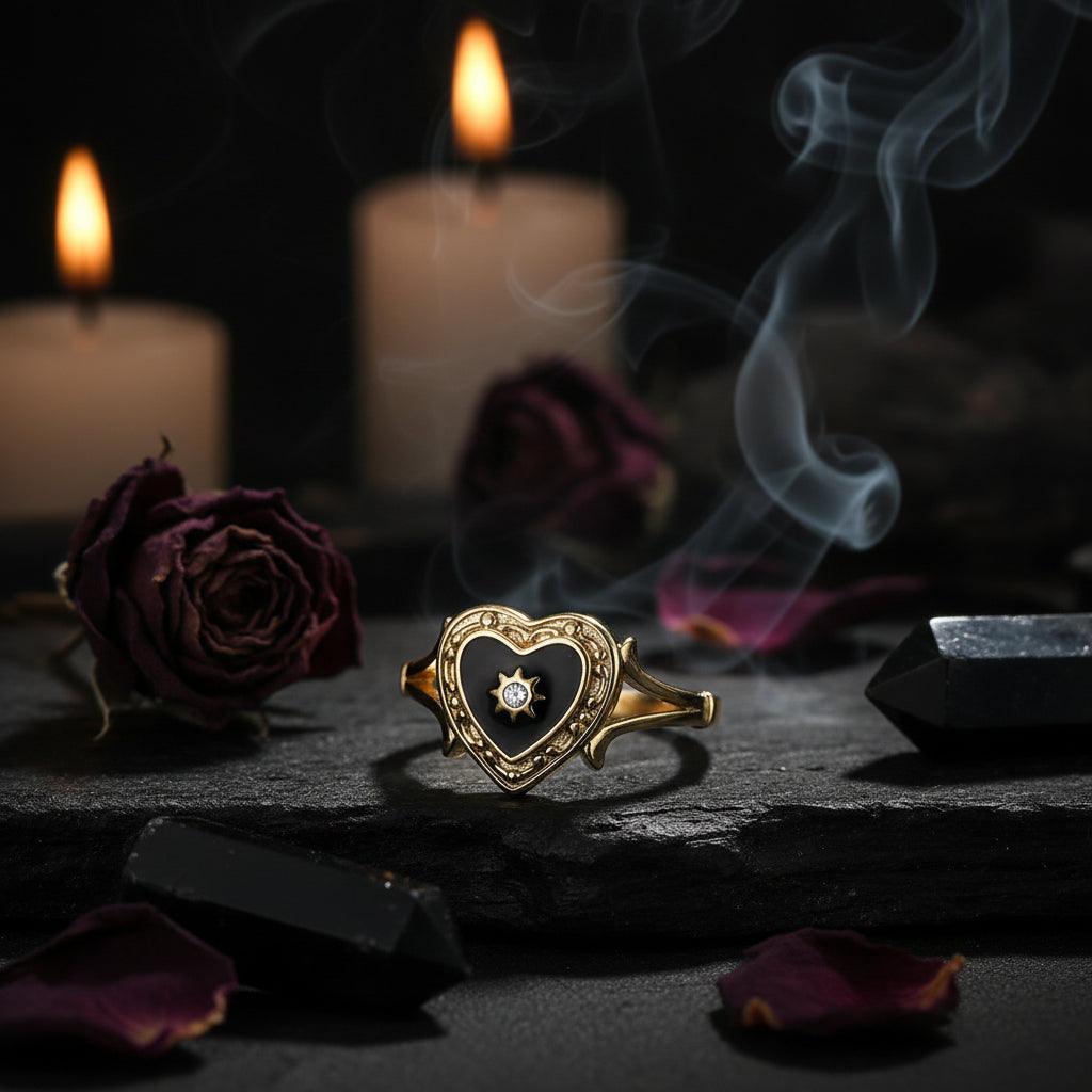 Gold ring with black heart-shaped stone and star detail on a white background