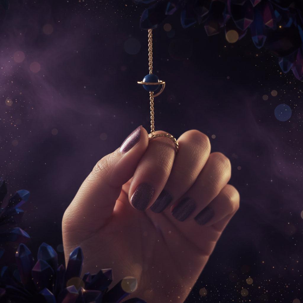 Hand holding a small blue stone on a string against a blurred green background