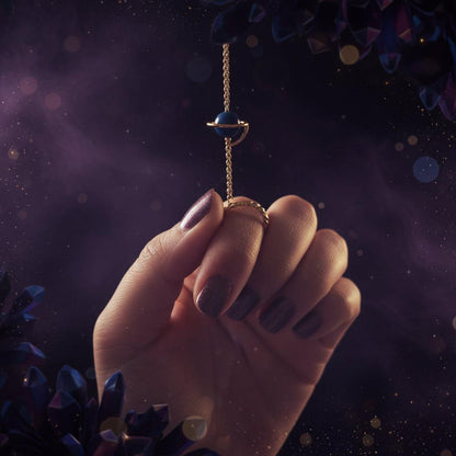 Hand holding a small blue stone on a string against a blurred green background