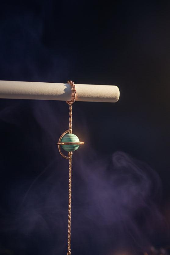 Bracelet with a turquoise bead and rose gold chain on a white surface.
