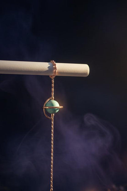 Bracelet with a turquoise bead and rose gold chain on a white surface.