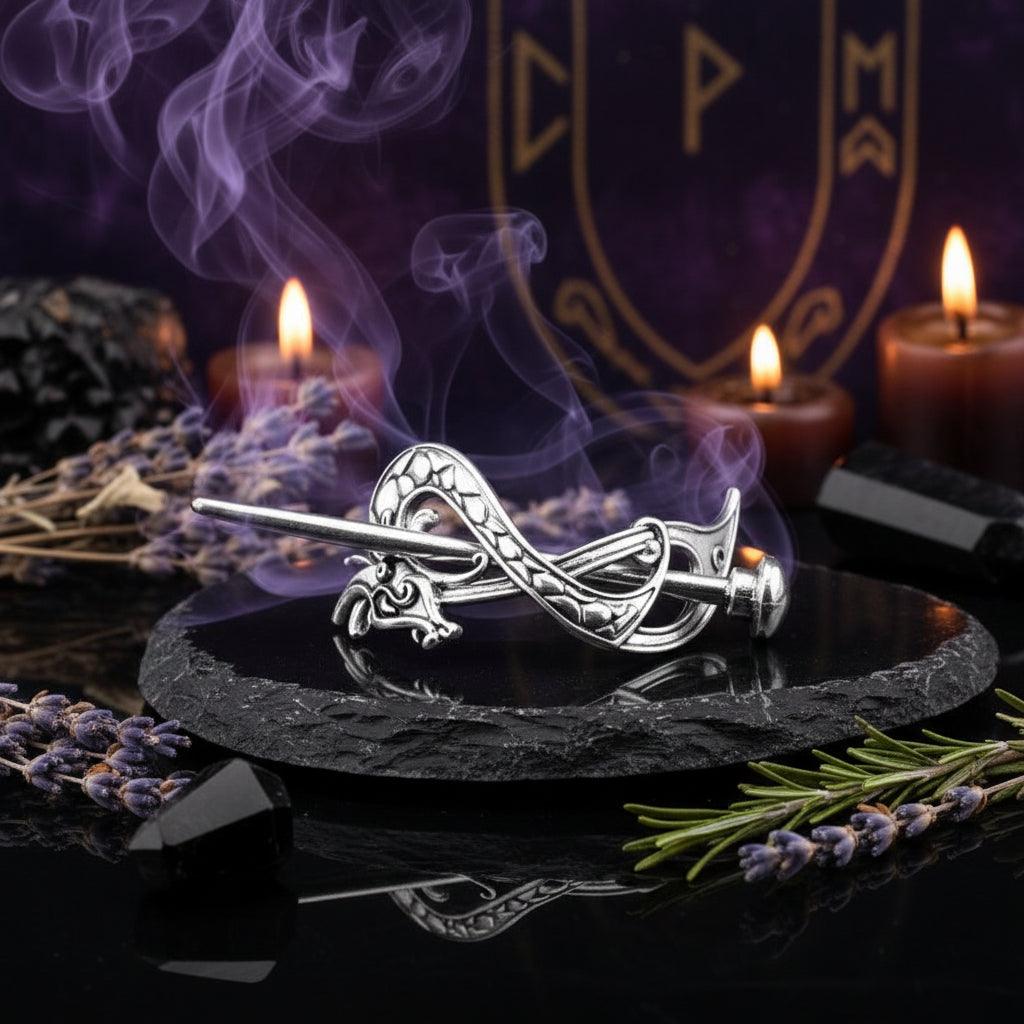Silver dragon-shaped brooch on a reflective black surface