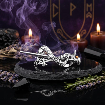 Silver dragon-shaped brooch on a reflective black surface