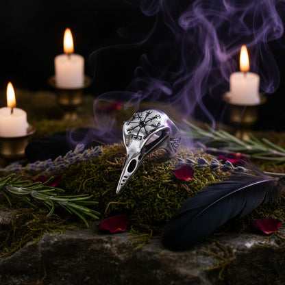 Silver raven skull ring with intricate designs on a dark background