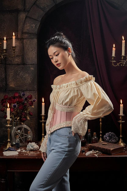 Woman wearing a beige off-shoulder top with lace details indoors.