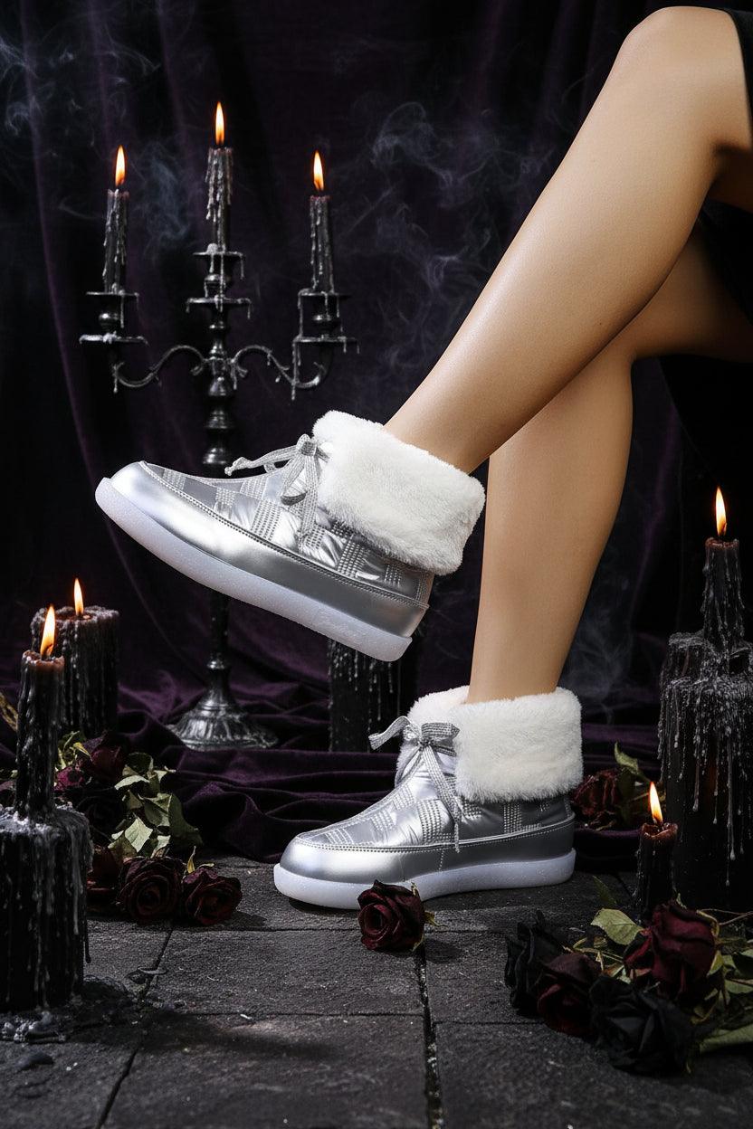 Silver sneakers with white fur lining worn by a person, against a textured gray background.