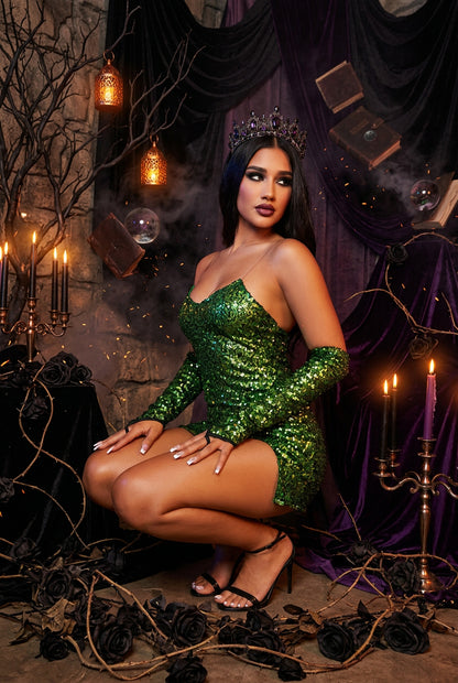Woman in a green sequin dress surrounded by foliage and decorative elements.