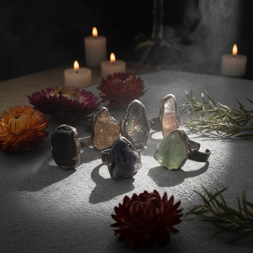 Set of unique stone rings on a textured surface with flowers and leaves.