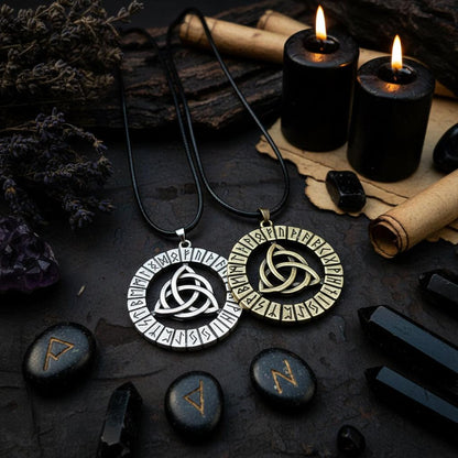 Two circular pendants with leaf designs and runic inscriptions on a dark fabric background.