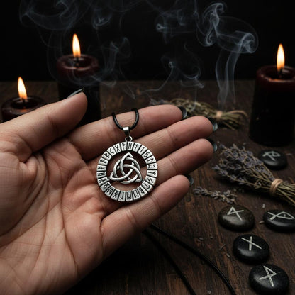 Silver pendant with Celtic knot and runic designs held in a hand against a dark background