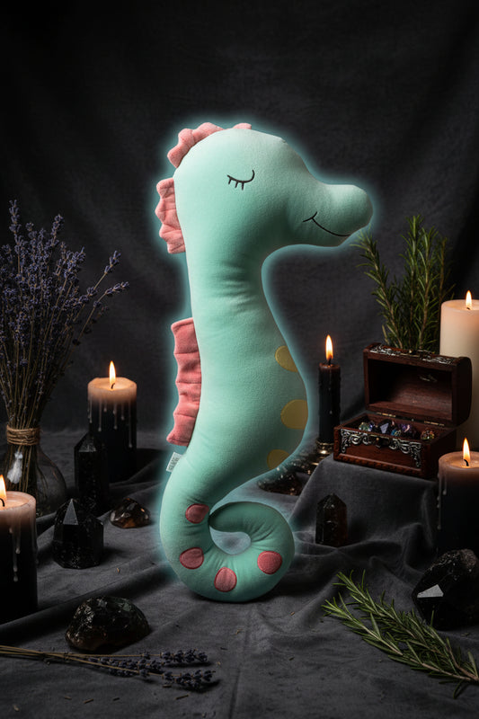 Plush toy seahorse with pink fins on a light background