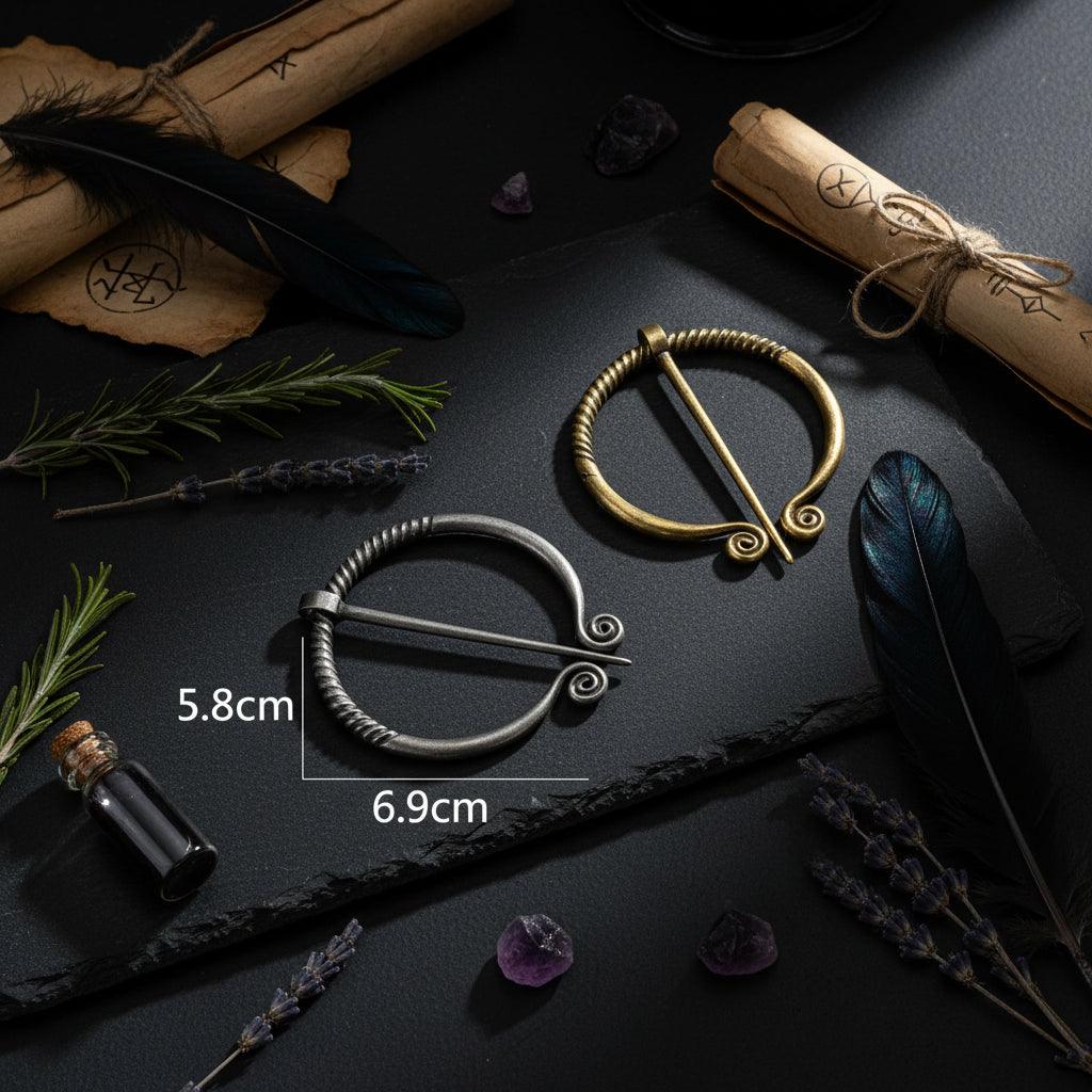 Two metal brooches, one gold and one silver, with measurements on a white background.