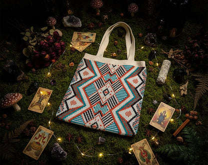 Colorful patterned bag held by a hand on a white surface with a beige coat in the background