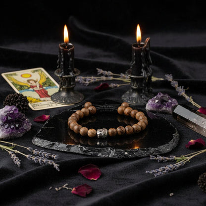 Wooden beaded bracelet with a silver Buddha charm on a textured surface