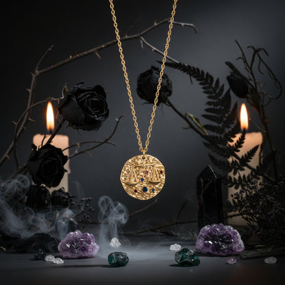 Gold necklace with a round pendant featuring gemstones on a white background