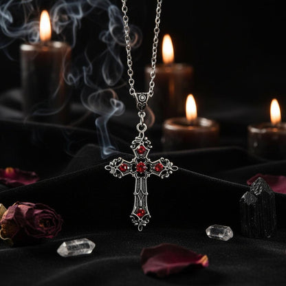 Silver cross necklace with red stones on a white background