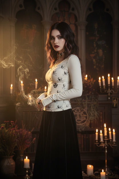Person wearing a white dress with skull patterns in a room with bags and a Hello Kitty poster.