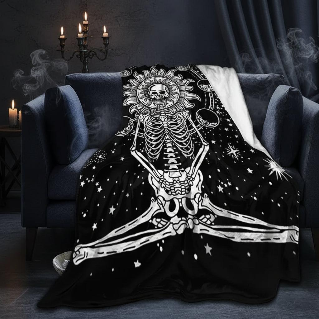 A black throw blanket with a white skeleton design draped over a dark gray armchair in a living room setting.