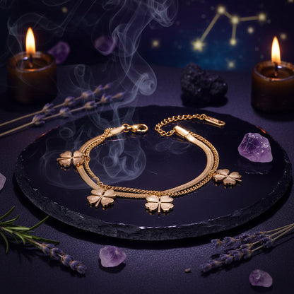 Gold bracelet with four-leaf clover charms on a beige box