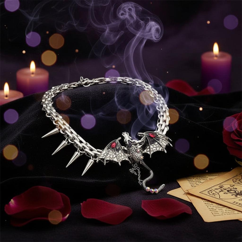 A gothic-style silver chain bracelet featuring a detailed dragon pendant with red eyes, a small knight figure, and five sharp metallic spikes, displayed on a reflective black surface.