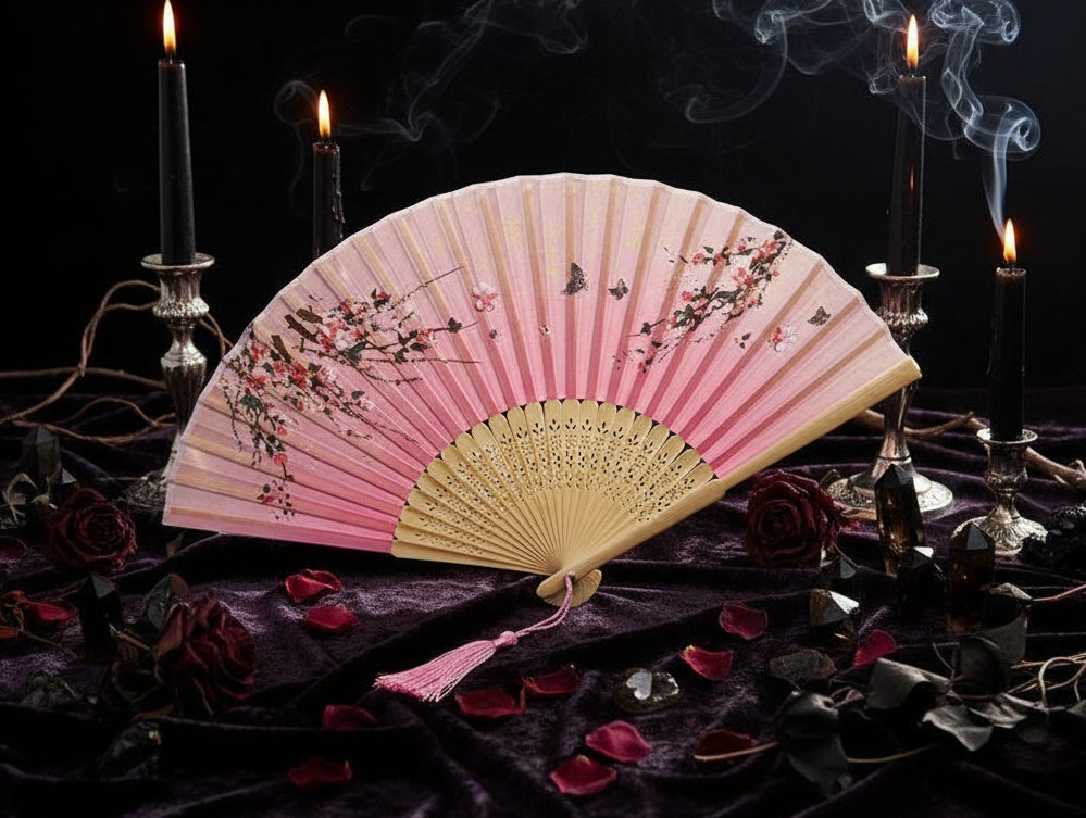 Pink and white hand fan with floral design on a light background