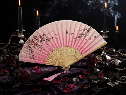 Pink and white hand fan with floral design on a light background