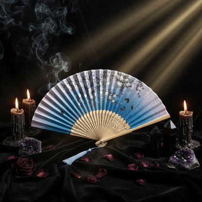 Traditional folding fan with artistic design on a light background with pink flowers.
