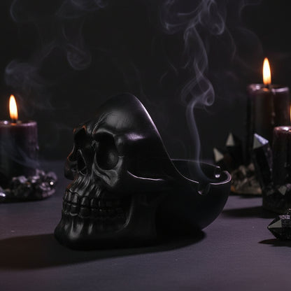 Black skull-shaped ashtray with a cigarette inside on a white background
