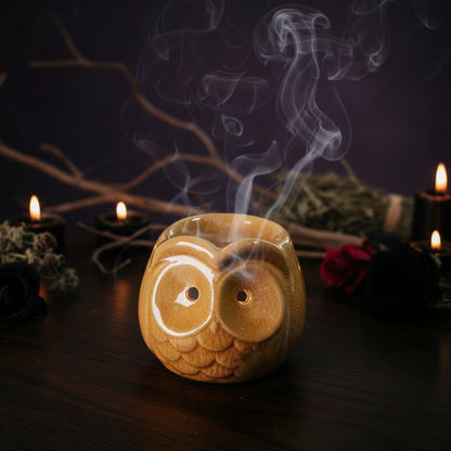 Ceramic owl-shaped candle holder on a wooden surface with blurred background