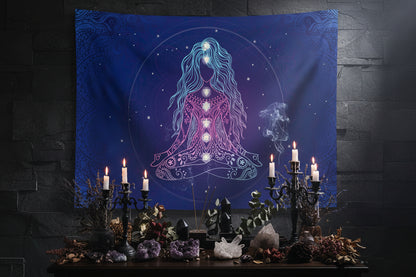 A large wall tapestry featuring a meditating figure with glowing chakras on a deep blue cosmic background, displayed in a modern living room setting above a white sectional sofa.