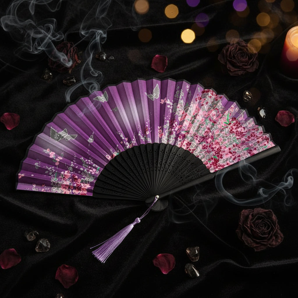 Floral-patterned folding fan with black handle and purple accents on a white background with pink flowers.