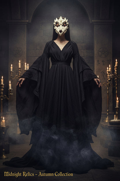 A skull-style costume mask with sharp pointed teeth and hollow eye sockets, photographed against a dark black background.