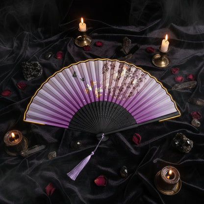 A traditional folding hand fan with a purple gradient and cherry blossom print, styled with pink flowers on a white background.