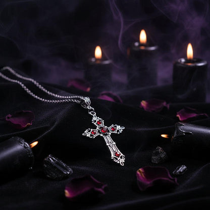 Silver cross pendant with red stones on a white background