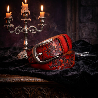 Red leather belt with black embossed design on a wooden surface